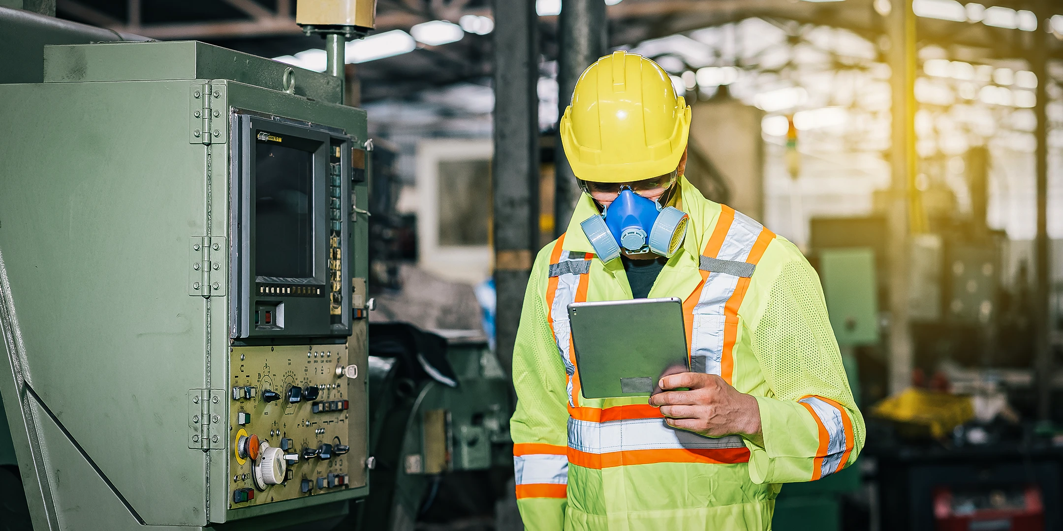 An employee wearing PPE and holding a tablet.
