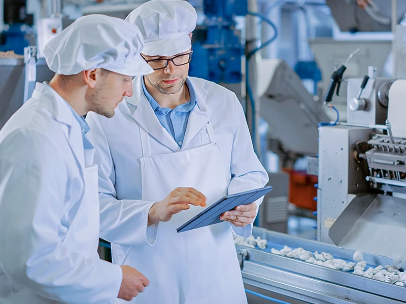 Zwei Personen überwachen die Lebensmittelproduktion am Tablet