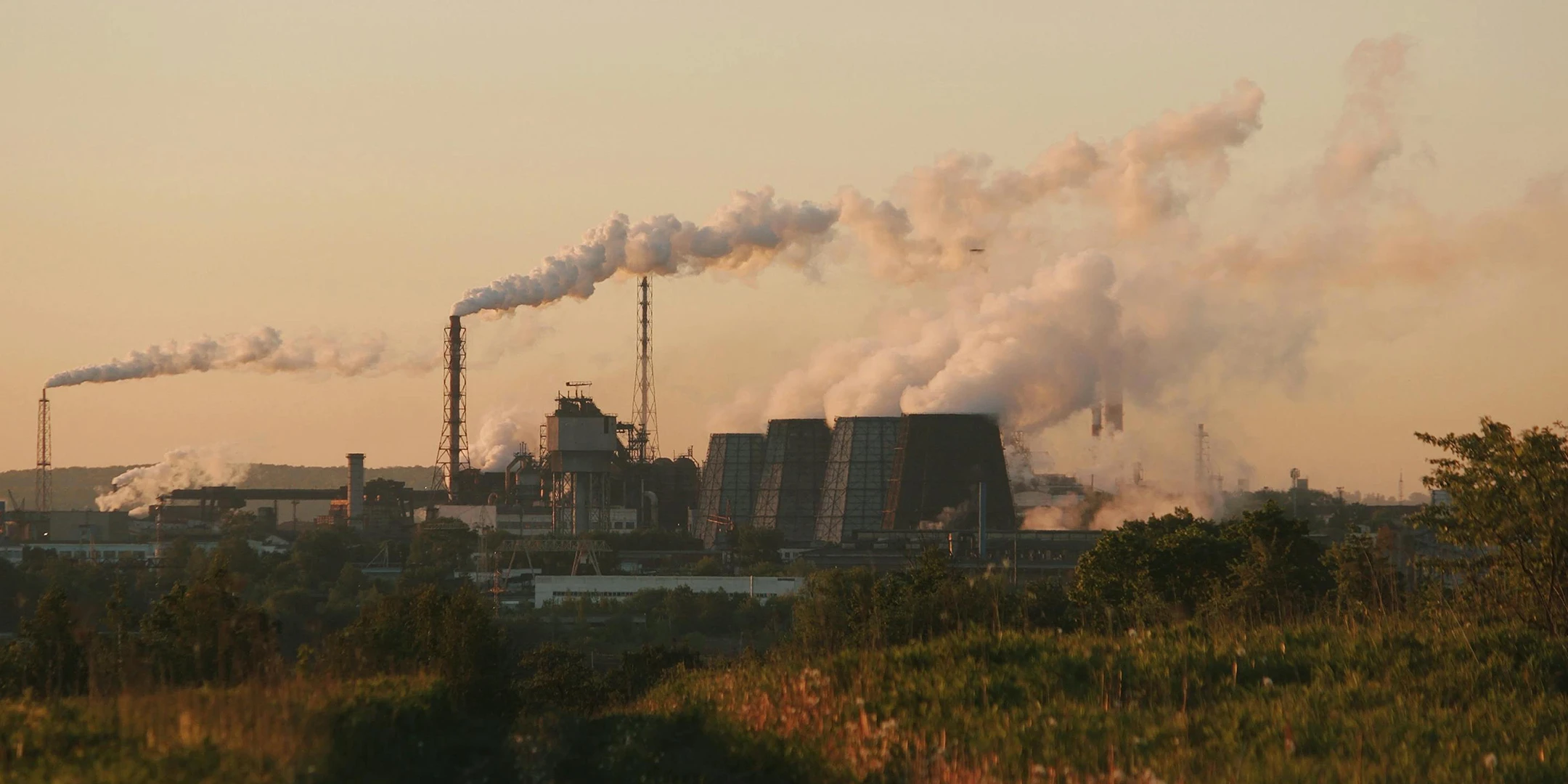 Eine Fabrik mit vielen Kühltürmen im Sonnenuntergang